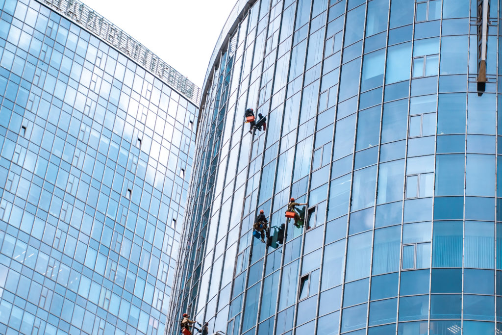 gente trabajando en la vertical de un edificio acristalado